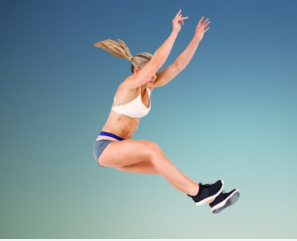A woman jumping in the air with her hands up.