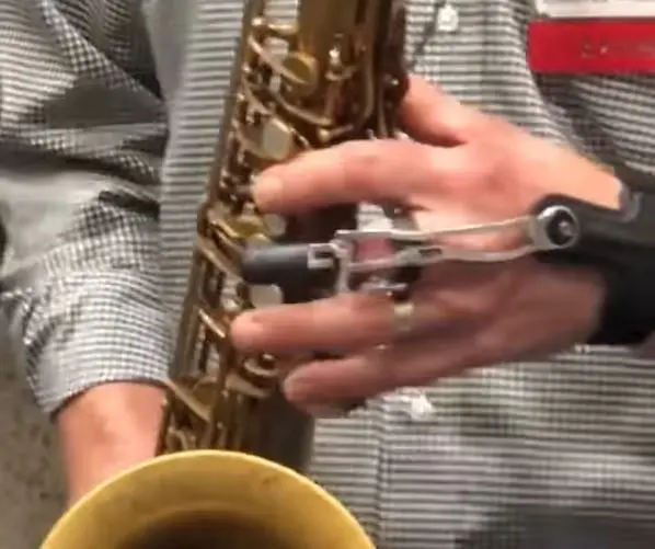 A person holding a saxophone with a string attached to it.